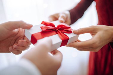 Sevgililer Günü konsepti. Elinde kırmızı kurdele olan bir hediye kutusu. Sevgili çift 14 Şubat 'ta birbirlerine hediyeler verir. Romantik erkek arkadaş ve kız arkadaş sevgililer gününü kutluyor.