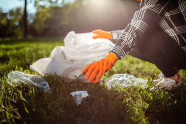Bir kadın kullanılmış plastik şişeyi toplayıp çöp torbasına koyar. Güneşli bir günde bir gönüllü parkı temizler. Temizlik, kirlilik, ekoloji ve plastik konsept
