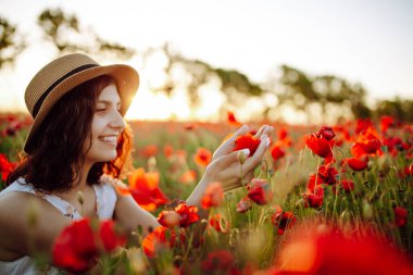 Şapka takan genç bir kadın gün batımında tarlanın ortasında kırmızı gelincik çiçeklerinin arasında oturuyor. Kız baharı seviyor, mutlu ve doğaya bağlı hissediyor. Özgürlük kavramı