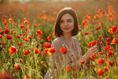 Bir kız tarlada gülümseyen kırmızı gelincik çiçekleri gibi oturur ve onları koklamaktan zevk alır. Genç bir kadın mutlu ve doğayla uyum içinde. Barış ve aşk kavramı