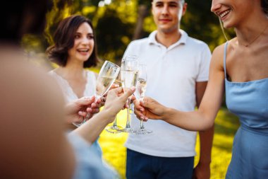 Düğün konukları kadeh tokuşturuyor. Düğün partisinde şampanya içen bir grup insan. Şık bir kutlamada konuklar kadeh kaldırıyor ve tezahürat yapıyor.