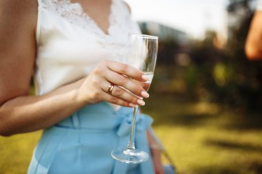 Partideki bir kızın elinde bir kadeh şampanya var. Elinde bir bardak şarap olan bir kadın. Yaz tatili, doğum günü, yıldönümü, düğün