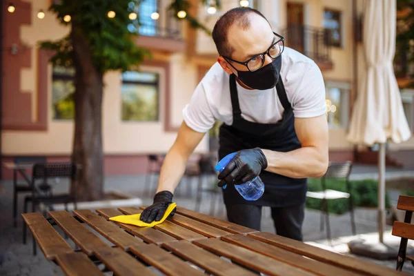 Camarero Limpiando Mesa Con Spray Desinfectante Usando Mascarilla Protectora Café — Foto de Stock