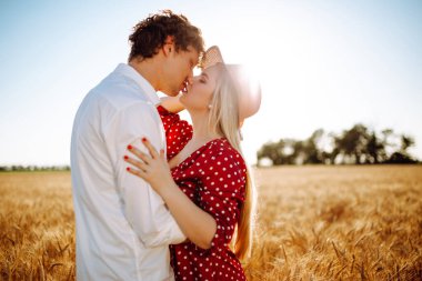 Gün batımında buğday tarlasında öpüşen sevgi dolu bir çift. Sıcak renkler. Hasır şapkalı bir kız ve beyaz gömlekli bir adam. Buğday tarlasında inanılmaz bir gün batımı. Gençlik, aşk ve yaşam tarzı kavramı