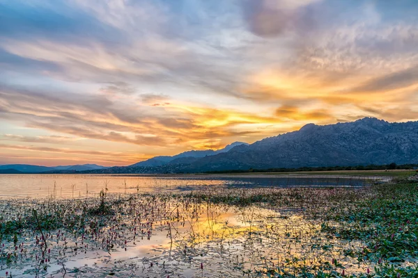 Colorful sunset reflected in the lake with the mountains at the background — Stock Photo, Image