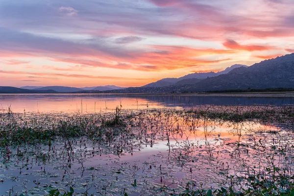 Colorful sunset reflected in the lake with the mountains at the background — Stock Photo, Image