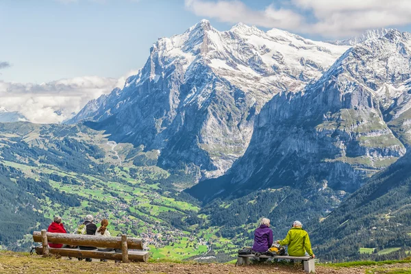 Randonneurs reposant sur un banc et profitant de la vue spectaculaire dans les Alpes suisses — Photo