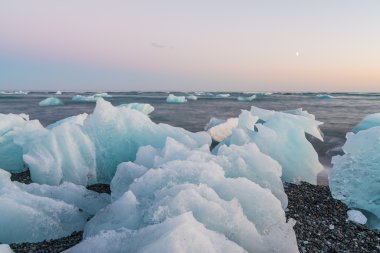 Jokulsarlon, İzlanda gün batımında siyah bir plajda buzdağları