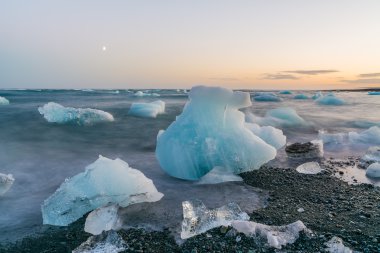 Jokulsarlon, İzlanda gün batımında siyah bir plajda buzdağları