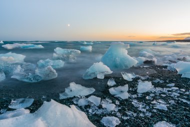 Jokulsarlon, İzlanda gün batımında siyah bir plajda buzdağları