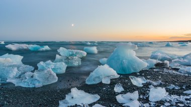 Jokulsarlon, İzlanda gün batımında siyah bir plajda buzdağları