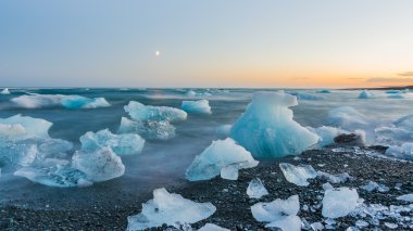 Jokulsarlon, İzlanda gün batımında siyah bir plajda buzdağları