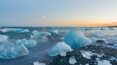 Jokulsarlon, İzlanda gün batımında siyah bir plajda buzdağları