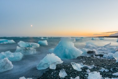 Jokulsarlon, İzlanda gün batımında siyah bir plajda buzdağları