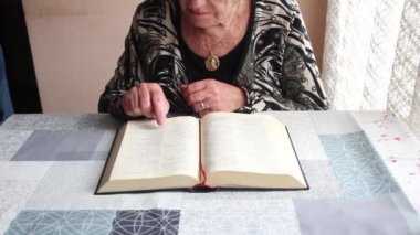 Boynunda Bakire Meryem 'in altın madalyonuyla İncil okuyan yaşlı bir kadın. Hıristiyanlık kavramı