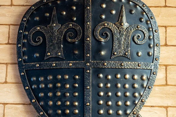 The interior design. A metal shield hangs on the wall as a decoration. Iron shield close up