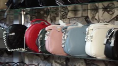 Mağazadaki raflarda çok renkli kadın çantaları var.