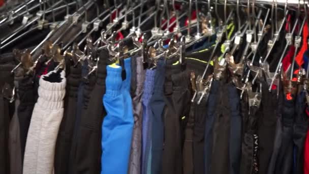 Много штанов висит на вешалке в магазине — стоковое видео