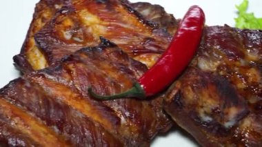 Kızarmış kaburga ve kırmızı biber beyaz tabakta.