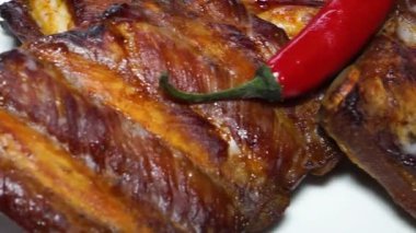 Kızarmış kaburga ve kırmızı biber beyaz tabakta.