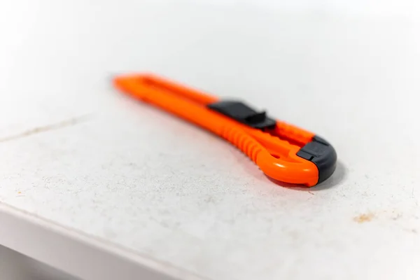 Un couteau de papeterie rouge repose sur un bureau blanc — Photo