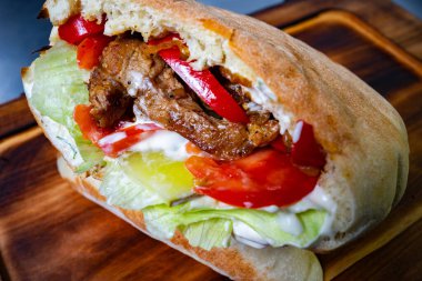 Izgara et, taze marul, domates ve biberle dolu nefis bir sandviç, hepsi de yumuşak ekmeğin içinde. Tatmin edici bir yemek için mükemmel..