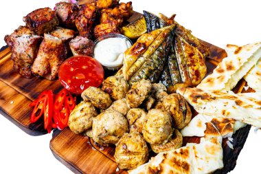 Lezzetli soslar, taze sebzeler ve ahşap bir tahtanın üzerinde ekmek eşliğinde ızgara et ve tavuk ziyafeti..