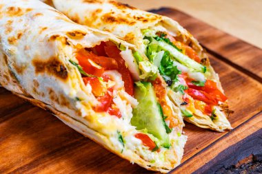 Tahta bir tahtanın üzerinde marul, domates ve salatalıkla dolu taze bir sebze ambalajı duruyor. Paketin kenarları çıtır çıtır ve renkli malzemeler var..