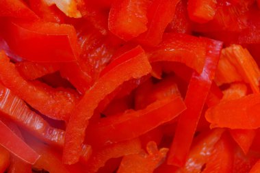 Parlak kırmızı dolma biberler şeritler halinde kesilir, salata, kızartma ya da çeşitli yemeklerde malzeme olarak kullanılmaya hazırdır..