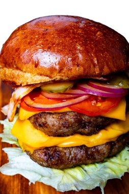 İki köfte, çedar peyniri, domuz pastırması, domates, marul, turşu ve soğanlı lezzetli bir burger..