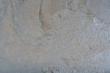 Gri beton bir yüzey, yakın zamanda dökülen ve kuruyan bir süreci gösteren çeşitli doku ve desenleri gösterir..