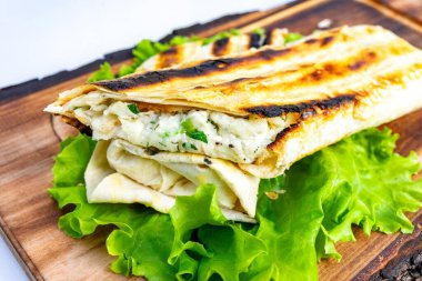 Düz ekmek ambalajı çeşitli malzemelerle doldurulur ve ızgara yapılır. Tahtaya konmuş taze marulla birlikte..