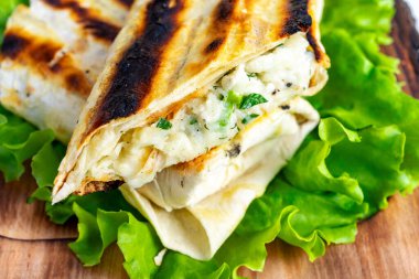 Flatbread erimiş peynir ve otlarla doludur, kahverengiye kadar kızartılır ve kıtır marulla servis edilir..