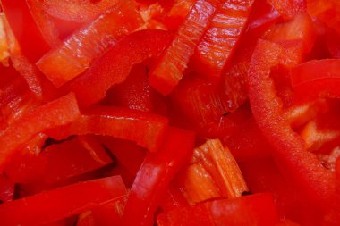 Kırmızı dolma biberler şeritlere ayrılır ve bir yüzeye yığılır. Taze ve canlılar..