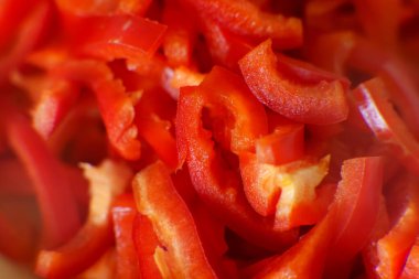 Kırmızı dolma biberler, mutfaktaki kesme tahtasının ince dilimlerine ayrılır. Güneş ışığı sebzelerin taze rengini gösterir..