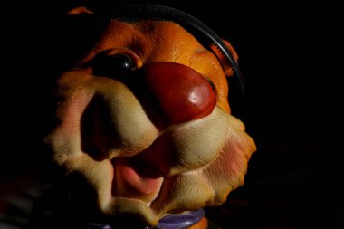 Gülümseyen yüzü ve şapkası olan oyuncak bir figür koyu bir arka plana yerleştirilir. Şeklin koyu renkleri vardır ve sahnenin odak noktasıdır..