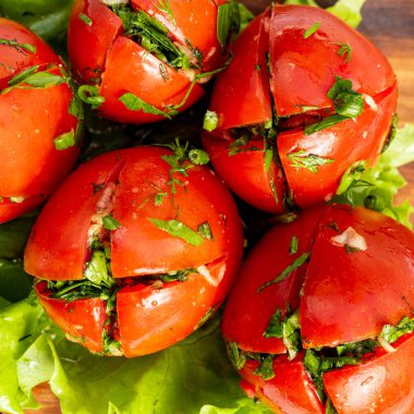 Domatesler kesilerek açılır ve yeşil otlarla doldurulur. Mutfaktaki kıvırcık salatanın üzerine konur. Bu kurulum servis edilmeye hazır..