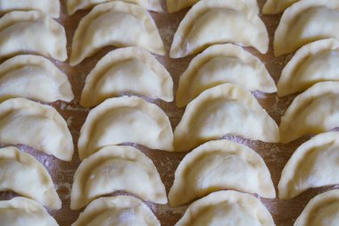 İşçiler hamur tatlısı yapar ve onları ahşap masaya düzgünce yerleştirirler. Daha sonra pişirmeye hazır olurlar..