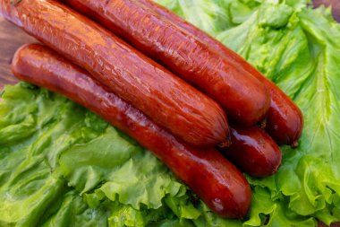 Marul yatağında dört sosisli, piknik ya da barbekü partisinde öğle yemeği için servis edilmeye hazır..