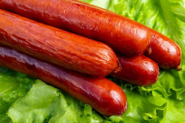 Sosisler yeşil marul yatağında uzanır, bir yemekte ya da bir açık hava etkinliğinde servis edilmeye hazırdırlar. Taze ve çekici görünüyorlar..