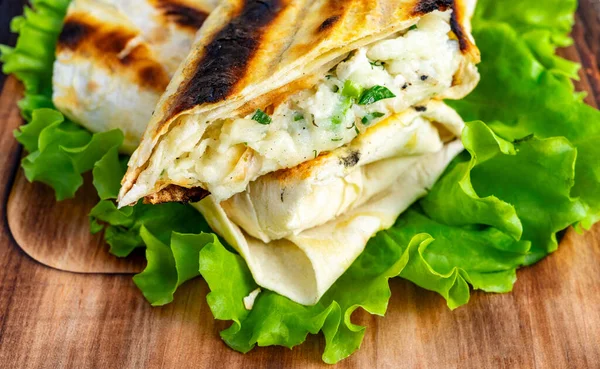 Flatbread is filled with melted cheese and herbs, then grilled and placed on lettuce. This dish is ready to enjoy as a light meal or snack.