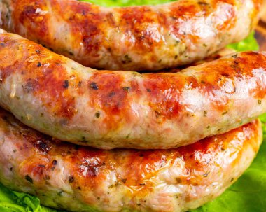 Sulu sosisler altın kahverengiye pişirilir ve taze marul yatağına yerleştirilir. Bu sahne yiyeceklerle dolu bir yazı yakalar..