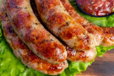 Sosisler ızgara yapılır ve taze marulun üzerine konur ve yakınlarda bir kase salsa sosu bulunur. Bu yemek hazır..