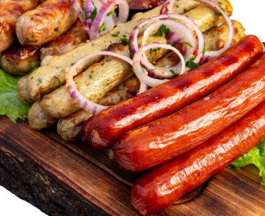 Sosisler dilimlenmiş soğan ve otlarla ahşap bir tabakta düzenlenir. Bu yemek hazırlıkları sırasında bir mutfakta gerçekleşir..