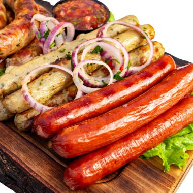 Sosisler ahşap bir tahtada düzenlenir. Yakınlarda soğan ve bir kase sos var. Aydınlık ve davetkar bir ortam..