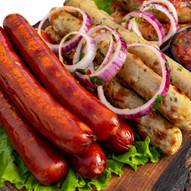 Sosisli ve sosis, marul ve soğan dilimleriyle birlikte ahşap bir tabakta servis edilir..