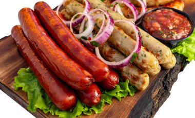 Sosisler marul ve soğanla ahşap bir tahtaya konur. Sosislerin yanında küçük bir kase sos var..