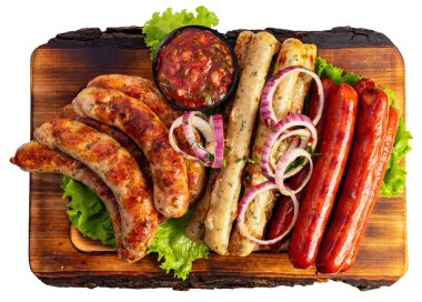 Çeşitli türde sosisler ahşap bir tahta üzerinde salsa sosu ve marul yatağında dilimlenmiş soğan ile sıralanır..