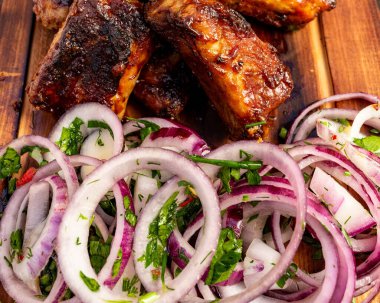 Tabakta taze soğan ve bitki salatasıyla ızgara et var. Bu yemek sıradan bir açık hava ortamında servis edilir..