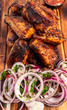 Hassas kaburgalar dilimlenmiş soğanlar ve küçük bir kase salsa sosunun yanında tahta bir tahtaya yerleştirilir. Bu yemek eğlenmeye hazır..